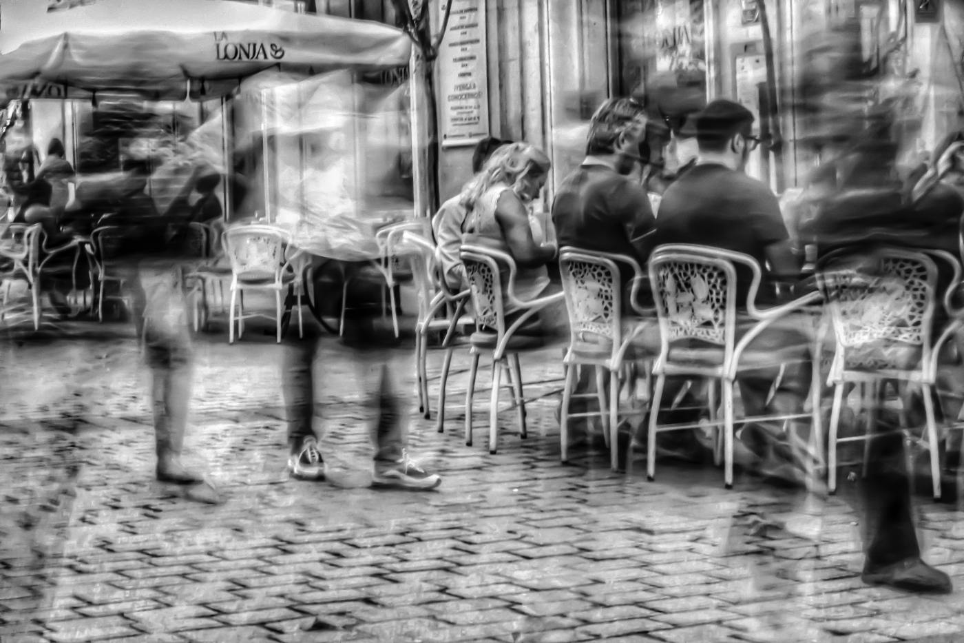Blurred figures of people walking past outdoor cafe tables